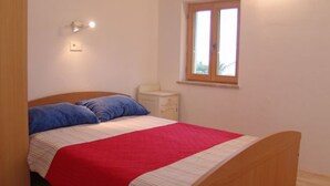 A bedroom with a single bed, a nightstand, a window, and a light fixture. - One Bedroom Apartment with Terrace (Savudrija)