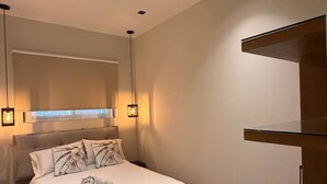 Ein modernes Schlafzimmer mit Bett, Nachttischen, Schminktisch und einem großen Spiegel.