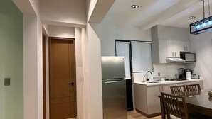 Eine moderne Küche mit Einbaukühlschrank, Mikrowelle und Herd. Im angrenzenden Essbereich befindet sich ein Esstisch mit Stühlen.