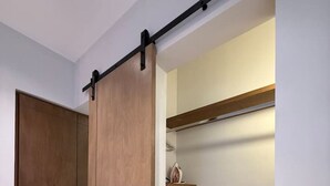 Ein moderner Kleiderschrank mit Schiebetür, eine Holzbank und ein Regal mit Spiegel und Dekorationselementen.