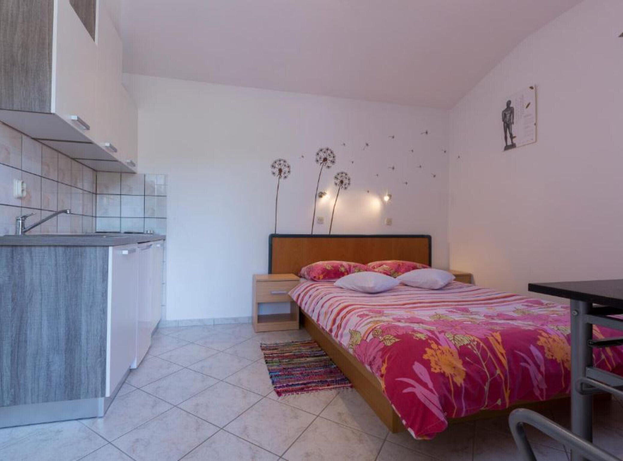 Une chambre compacte comprenant un lit, une table de chevet et un petit coin cuisine.