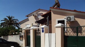 A building with a beige facade, green gates, and a satellite dish. - Mediterraneo Goga Apartments - TwoBedroom Apartment With Terrace (Mali Losinj)