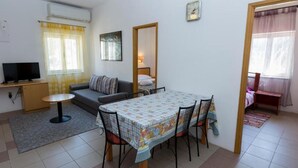 A compact living space with a sofa, a dining table with chairs, a television, and a mirror. - Mediterraneo Goga Apartments - TwoBedroom Apartment With Terrace (Mali Losinj)