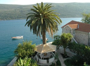 A coastal property with a view of the sea, a boat, and a palm tree. - Apartments Roza - One bedroom apartment with Garden view (Herceg Novi)