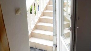 Una vista de una escalera que lleva a un espacio al aire libre con barandilla blanca y vegetación.