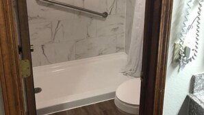 Une salle de bain avec douche, toilettes et murs en marbre.