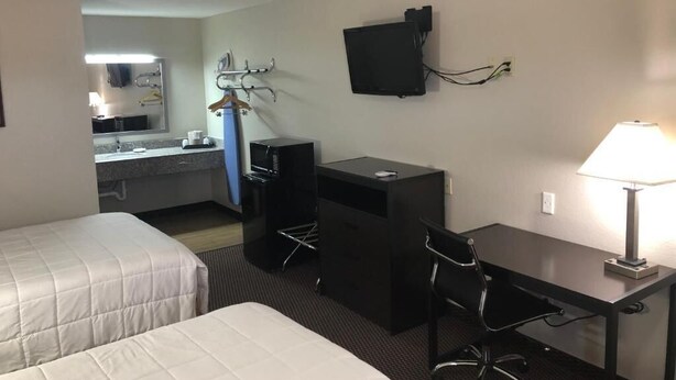 Une chambre d’hôtel avec deux lits, un bureau, une chaise, une télévision et une lampe.