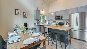 Una cocina moderna con electrodomésticos de acero inoxidable, una isla de madera y un comedor listo para cuatro.
