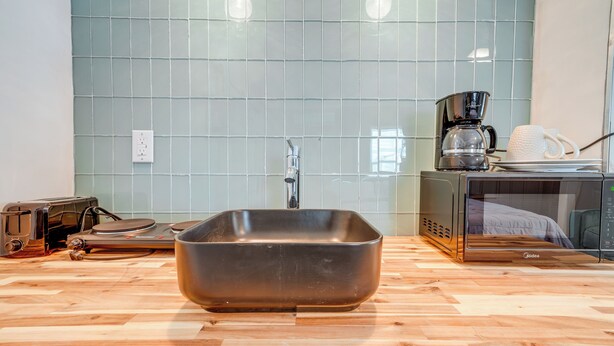 A modern kitchen with a large rectangular sink, a coffee maker, and a microwave on the counter. - Explore the Hinton Historic District! Luxe Studio (Hinton)