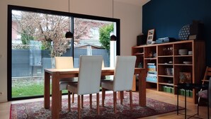 Ein Essbereich mit Holztisch und -stühlen, einem Bücherregal und Blick auf den Garten durch ein großes Fenster.