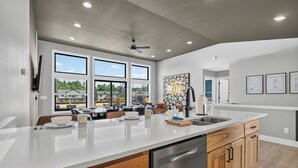 A modern kitchen with a large island, wooden cabinets, and a dishwasher. - *NEW*Private Chef-Family Friendly-Beach-Arcade Games-WI Dells (New Lisbon)