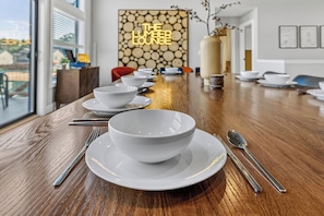 A dining table set with white bowls and plates, silverware, and a neon sign reading 'THE LUMBER LOUNGE'. - *NEW*Private Chef-Family Friendly-Beach-Arcade Games-WI Dells (New Lisbon)