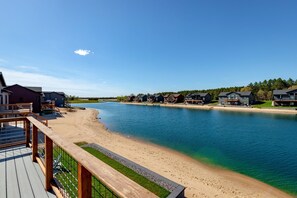 A lakeside property with a wooden deck, a sandy beach, and houses along the water's edge. - *NEW*Private Chef-Family Friendly-Beach-Arcade Games-WI Dells (New Lisbon)