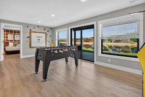 A room with a foosball table, a bed, and a window with a view of a building and a body of water. - *NEW*Private Chef-Family Friendly-Beach-Arcade Games-WI Dells (New Lisbon)