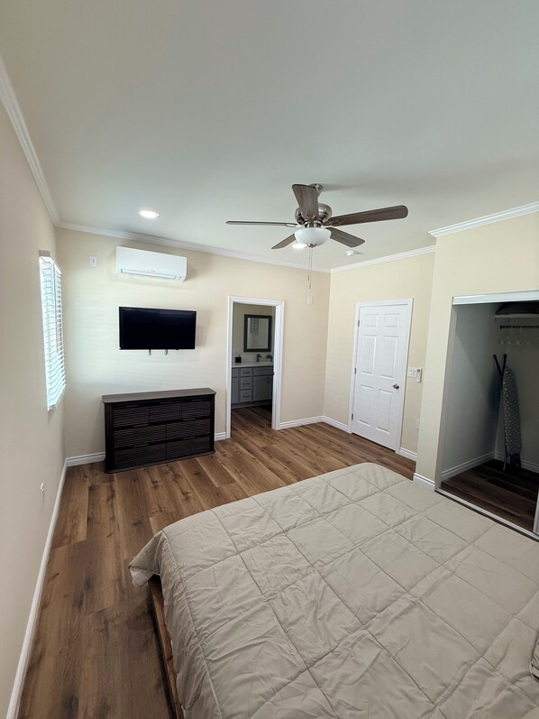 Quarto com cama, ventoinha no teto, ar condicionado, televisão, closet espaçoso e banheiro com espelho.