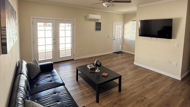 A spacious living room with a black leather sofa, a coffee table, a ceiling fan, and a flat-screen TV mounted on the wall. - Modern 3BR LA Home near Downtown LA, Perfect for Families and Large Groups (Los Angeles)