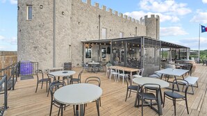 A stone building with a wooden deck, tables, and chairs. - Presidio Hotel - 2nd Floor (Johnson City)