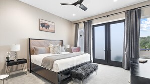 A modern bedroom with a bed, bedside tables, a bench, a ceiling fan, and a large sliding glass door to the outside. - Presidio Hotel - 2 Story Suite (Johnson City)