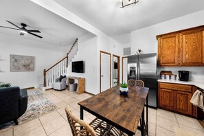 Una cocina moderna con armarios de madera, un refrigerador de acero inoxidable y un comedor con mesa y sillas de madera.