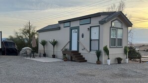 Et lille, etplans hus med en veranda, en trappe til indgangen og en grusbelagt indkørsel.