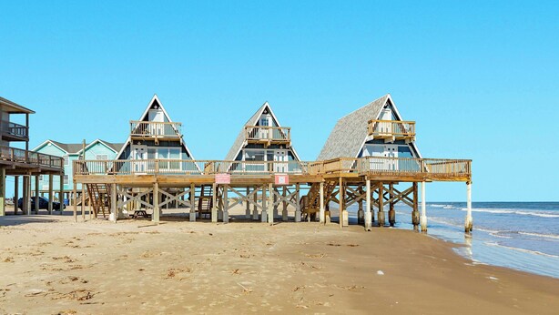 A beachfront property with three wooden deck structures, each with a triangular roof and a balcony. - Iconic A Frame Directly Over The Surfside Waves (Surfside Beach)