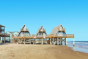 A beachfront property with three wooden deck structures, each with a triangular roof and a balcony. - Sleep Right Over the Waves, Iconic A Frame (Surfside Beach)