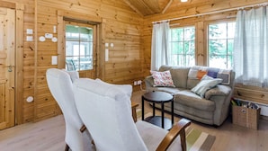 A cozy cabin interior with a wooden interior, a sofa, a chair, and a small table. - Kuikkaranta by Interhome (Juuka)