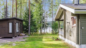 A cabin with a porch and a small shed, surrounded by a grassy yard and trees. - Kuikkaranta by Interhome (Juuka)