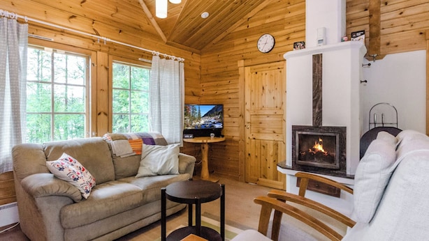 A cozy cabin interior with a sofa, a chair, a TV, and a fireplace. - Kuikkaranta by Interhome (Juuka)