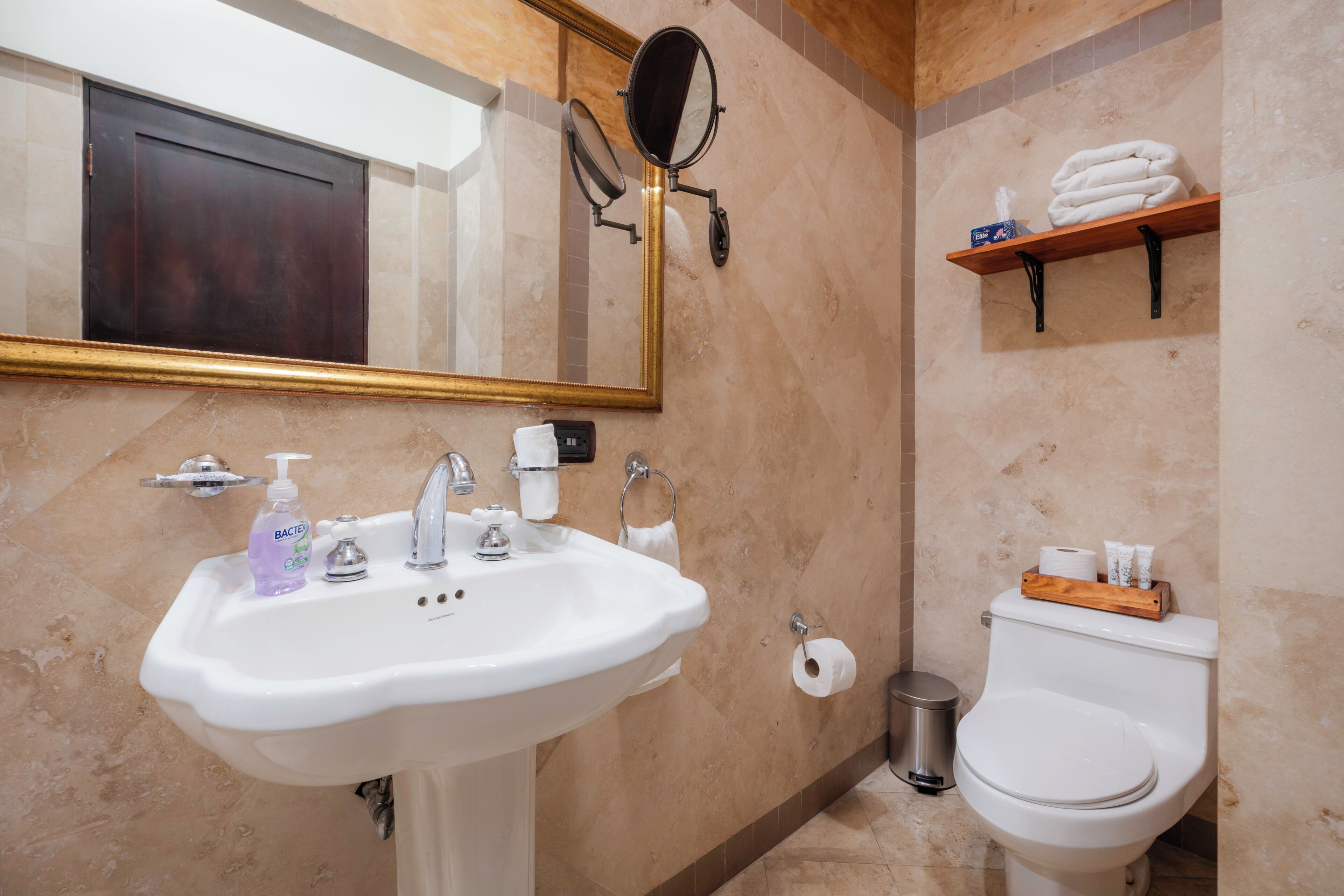 Une salle de bain équipée d’un lavabo, d’un miroir, de toilettes et d’un porte-serviettes.