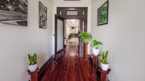 A hallway with wooden flooring, framed pictures on the walls, and potted plants. - Hotel in San Jose Hotel Majestad (San Jose)