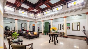 A spacious lobby with a high ceiling, large windows, and a central seating area with a sofa and chairs. - Hotel in San Jose Hotel Majestad (San Jose)