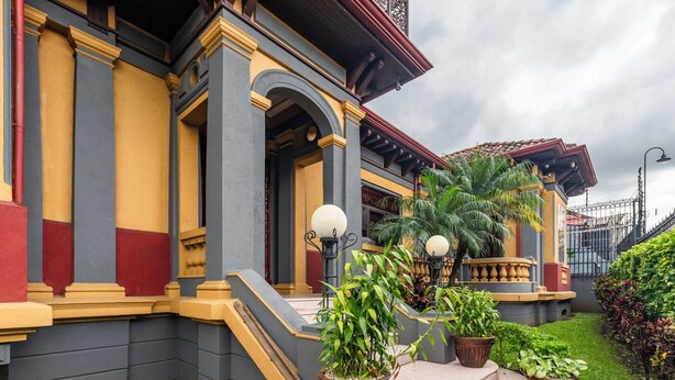 A building with a grand entrance, steps leading up to a covered area, and potted plants. - Hotel in San Jose Hotel Majestad (San Jose)