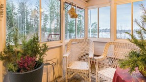 A cozy room with large windows, wicker chairs, and a table with a red tablecloth. - Vacation home Metsis by Interhome (Nurmes)