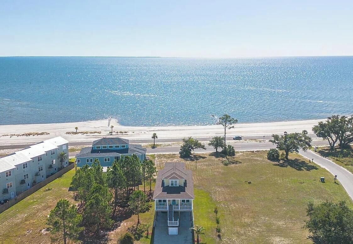 An aerial view of a coastal property with a large building, a smaller house, and a beach in the background.