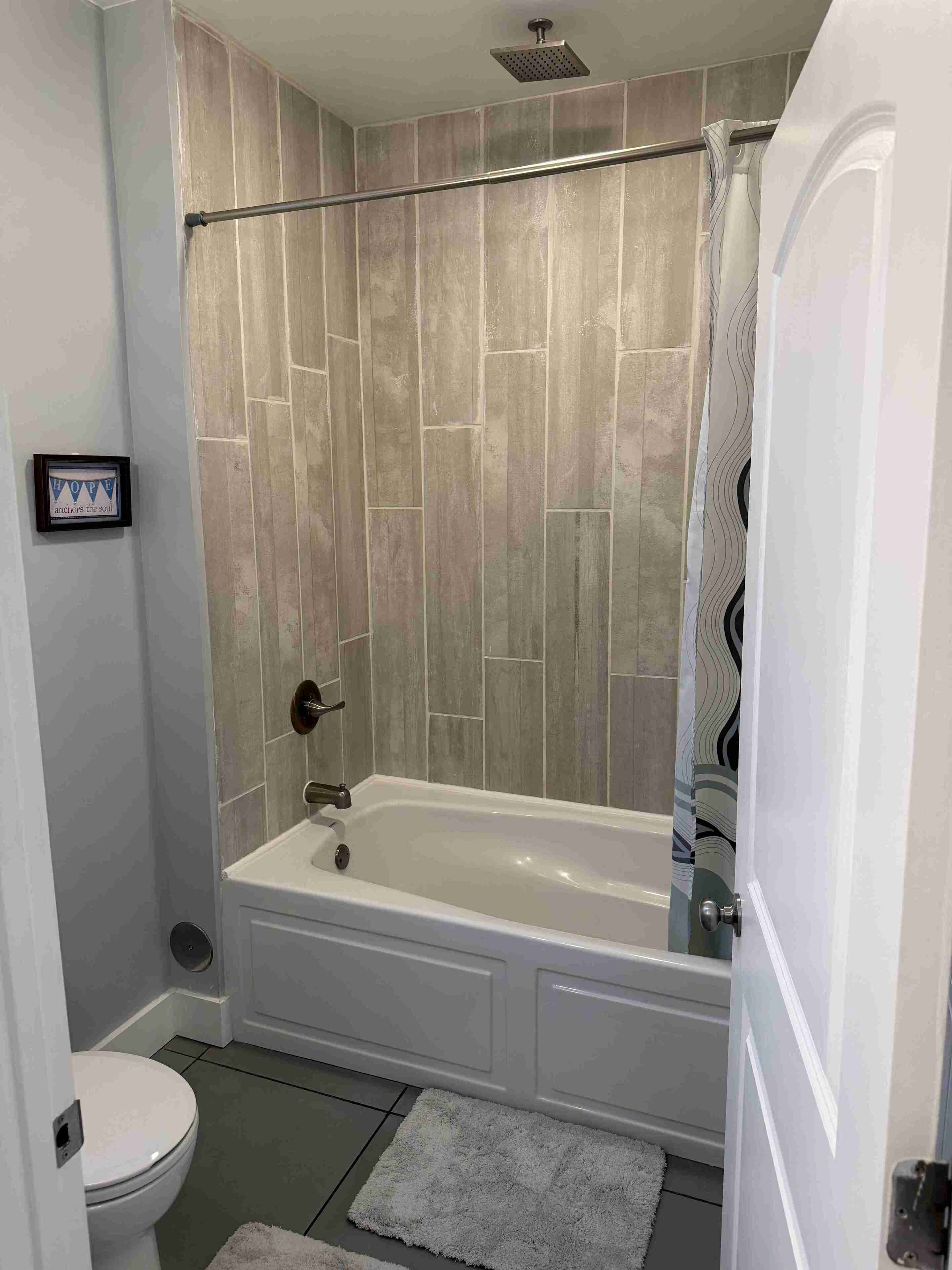 A bathroom with a bathtub, toilet, and shower curtain.