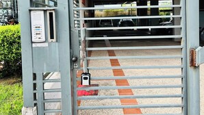 A gated entrance to a building with a metal gate and a keypad lock.