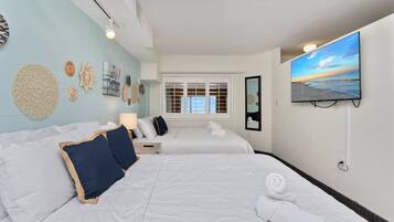 A hotel room with two beds, a TV, a window with blinds, and wall decor.