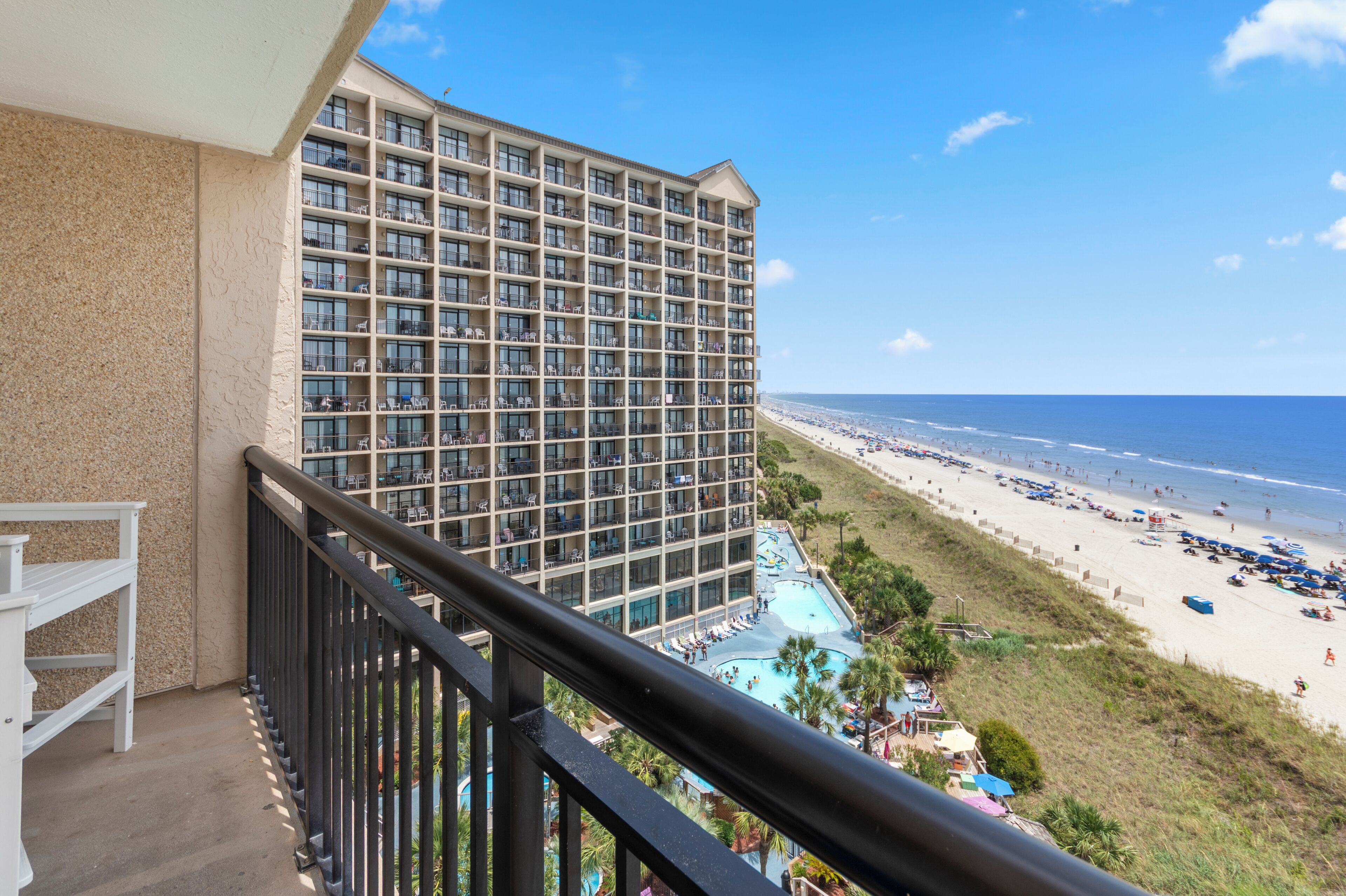 A high-rise hotel with a pool area and beach view.