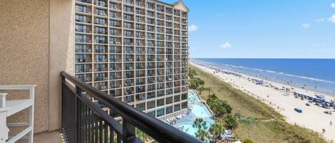 A high-rise hotel with a pool area and beach view.