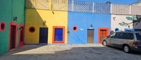 A courtyard with colorful buildings, a parked car, and a dog.