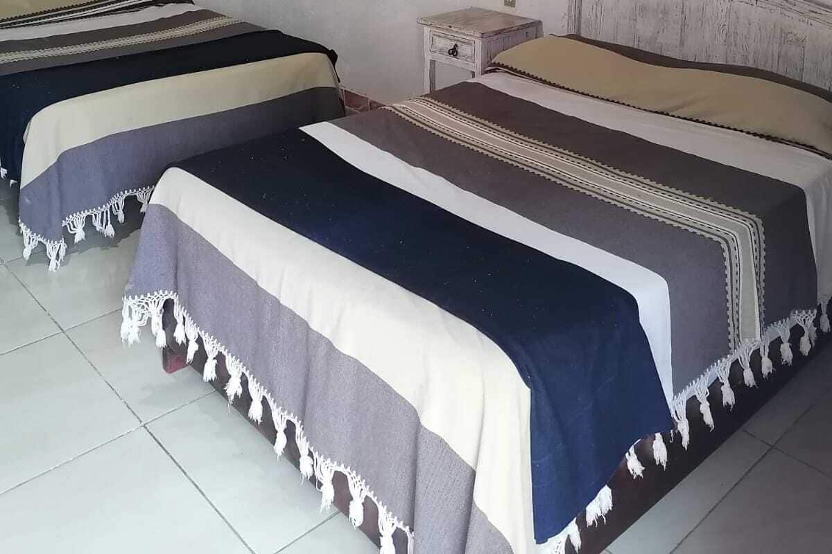 A room with two beds, a nightstand, a wall-mounted lamp, and three posters on the wall.