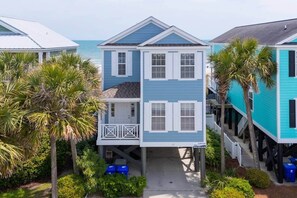A two-story beachfront house with a balcony, palm trees, and a view of the ocean. - Sea Salt - Surfside Beach (Surfside Beach)