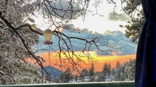 Ein Balkon mit Blick auf einen Sonnenuntergang über einer verschneiten Landschaft.