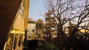 Ein Gebäude mit einem geneigten Dach und einem Balkon mit Tisch und Stühlen.