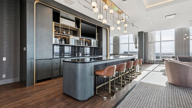A modern kitchen with a central island, bar stools, and pendant lighting. - Stylish 1-Bedroom Apartment in Calgary | BLVD Beltline (Calgary)