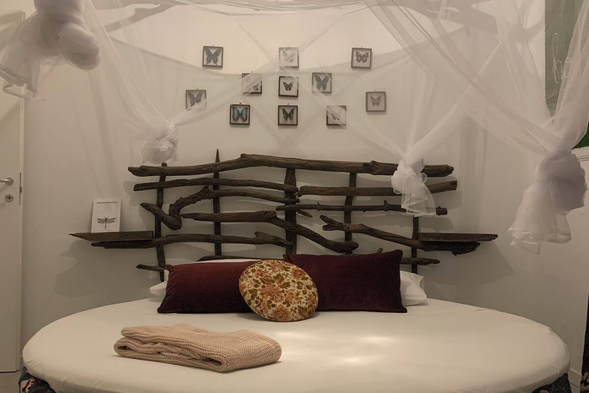 A bed with a white mattress, a floral-patterned duvet, and a red pillow.
