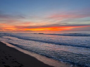 Una playa con olas al atardecer.