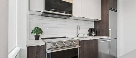 Una cocina moderna con horno empotrado, microondas, cafetera y refrigerador.