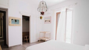 A bedroom with a bed, a wooden bench, a hanging light fixture, and a door leading to a closet.